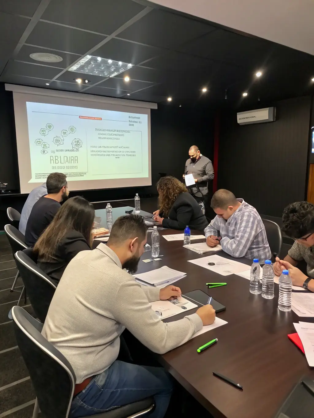 A group of local business owners attending an AGCLA workshop, focused on improving their financial management skills, with a facilitator guiding the session.